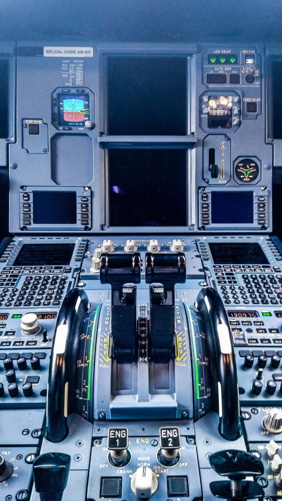 Modern airliner cockpit with vibrant digital displays and illuminated controls in blue and gray Wallpaper