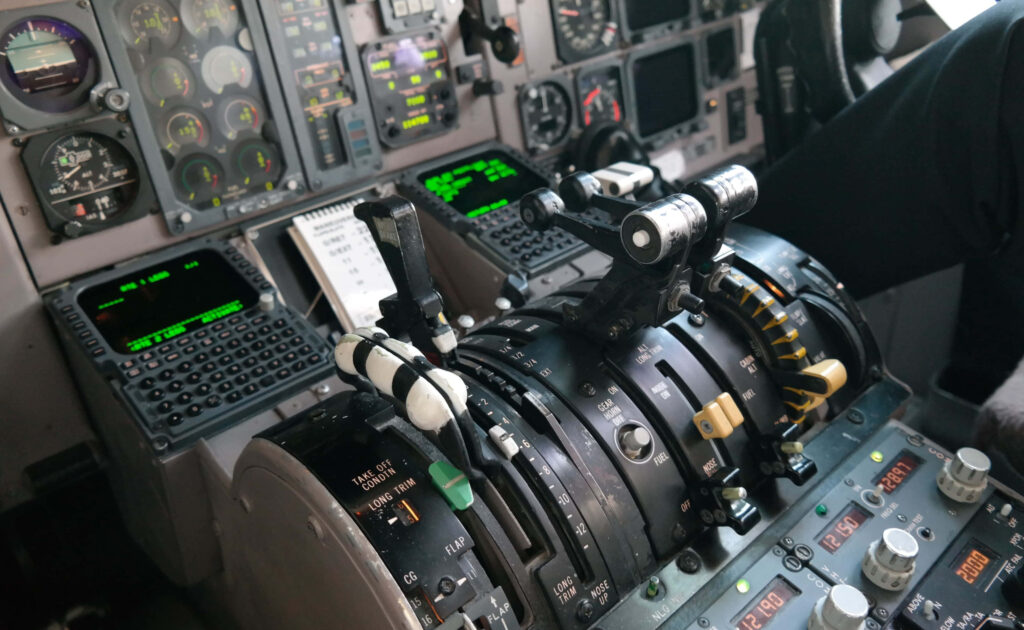 Close-up of airplane cockpit throttle controls and illuminated instruments with detailed digital displays Wallpaper