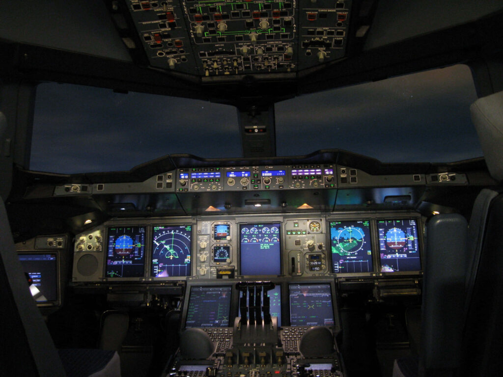 Modern airplane cockpit at night with glowing digital instruments and vibrant display screens Wallpaper