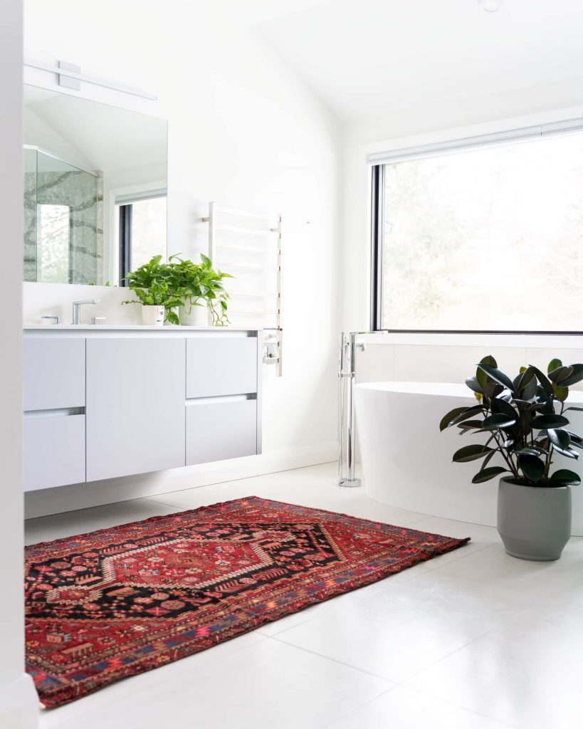 Bright modern all-white bathroom with freestanding tub red oriental rug and lush greenery Wallpaper