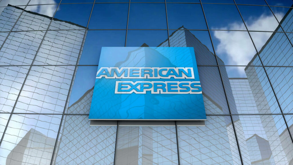American Express logo on blue sign reflected in glass facade of modern city skyscraper wallpaper