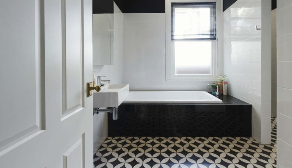 Modern bathroom with black and white patterned floor tiles sleek wall-mounted sink and built-in tub Wallpaper