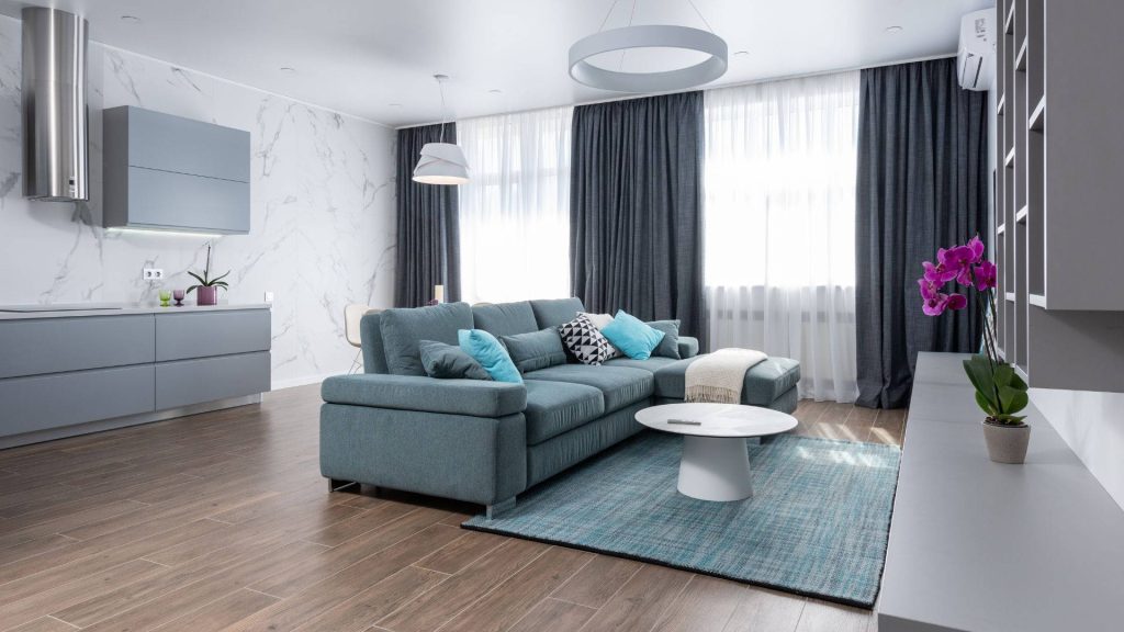 Modern open-plan living room with blue grey sectional couch white coffee table and marble accents Wallpaper