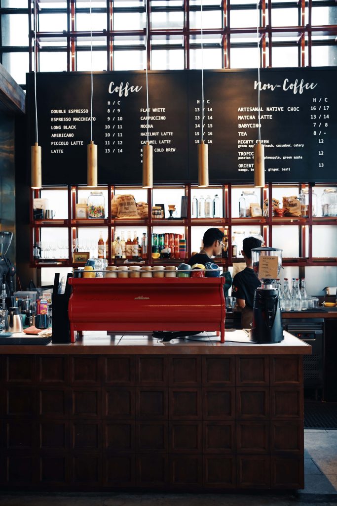 Modern coffee shop interior with red espresso machine and cozy baristas at wooden counter Wallpaper