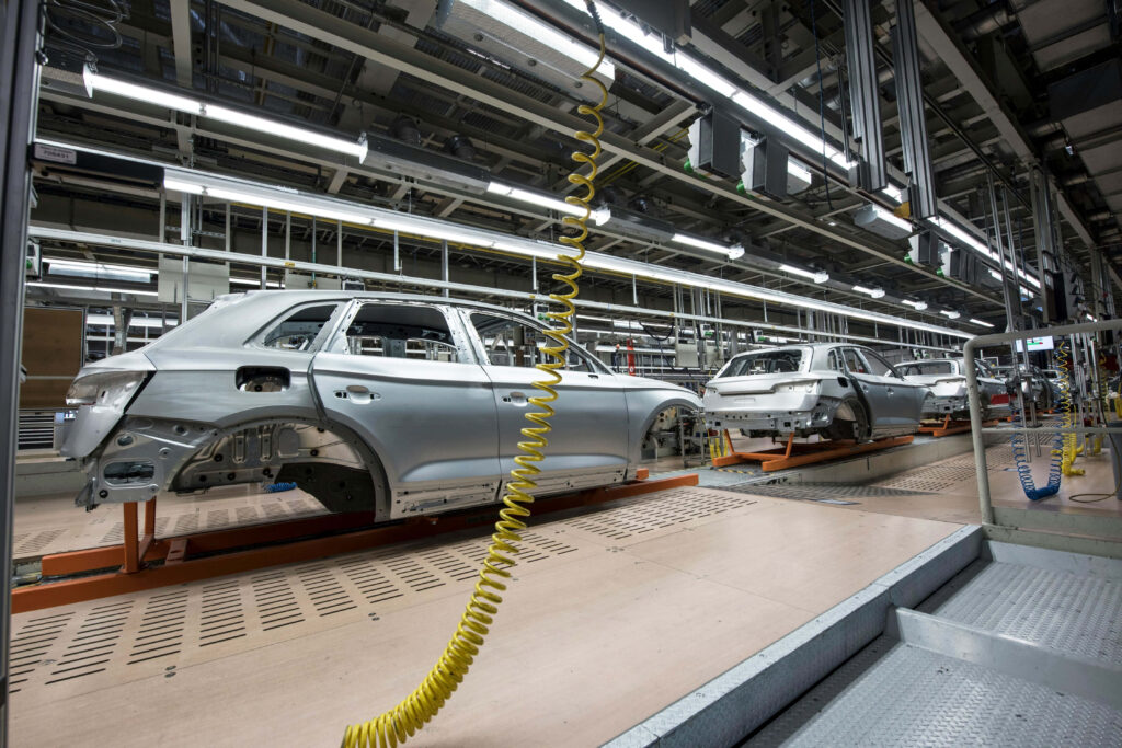 Modern car factory assembly line with metallic frames bright lighting advanced automotive manufacturing Wallpaper