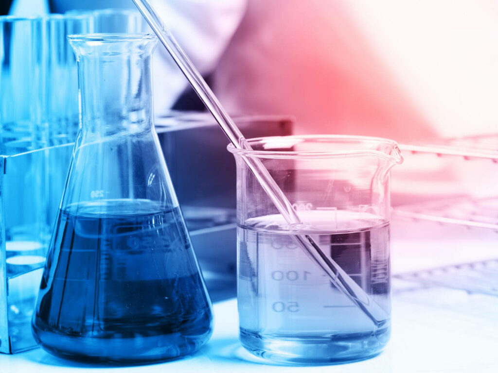 Close-up of lab glassware with blue liquid and stirring rod in blue pink lighting chemistry wallpaper