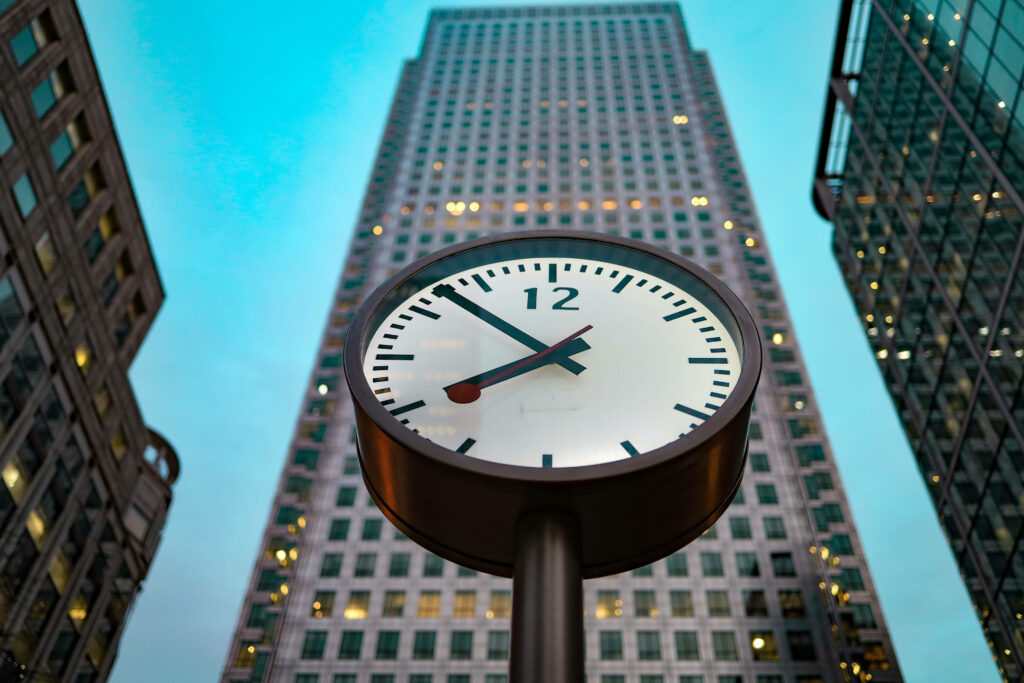 Modern cityscape at dusk with minimalist clock and glass buildings reflecting evening sky wallpaper