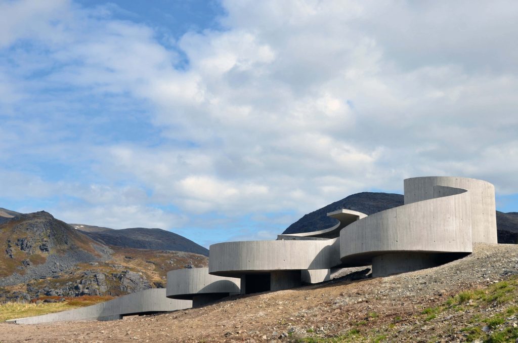 Modern concrete architecture with organic curves on rugged mountain landscape background wallpaper