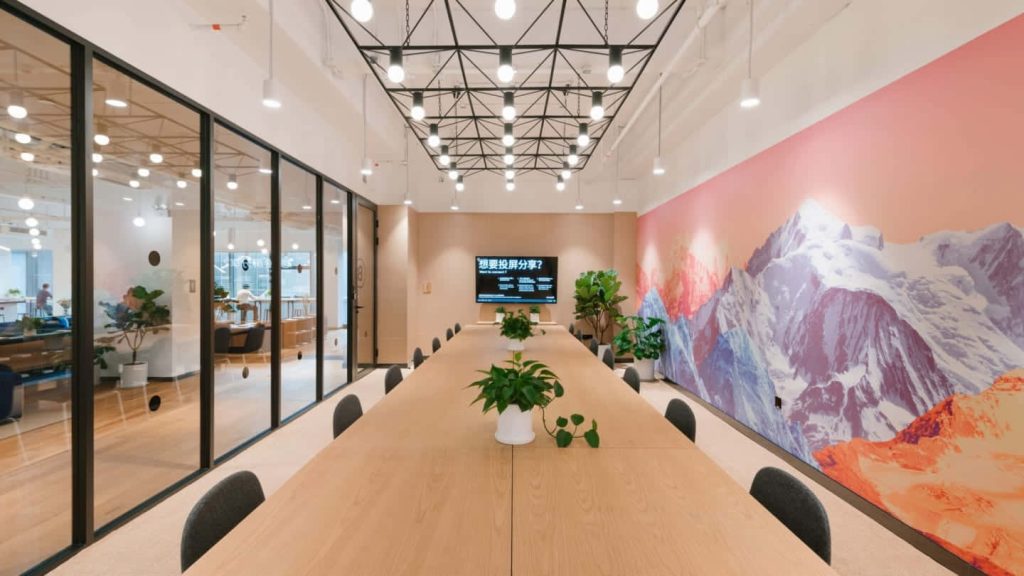 Modern conference room Zoom background with wooden table and vibrant mountain landscape mural Wallpaper