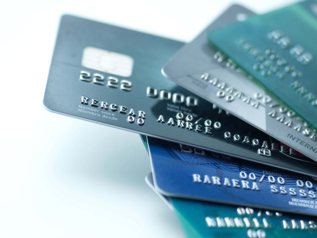 Stack of blue gray silver credit cards with embossed numbers on clean white background financial Wallpaper