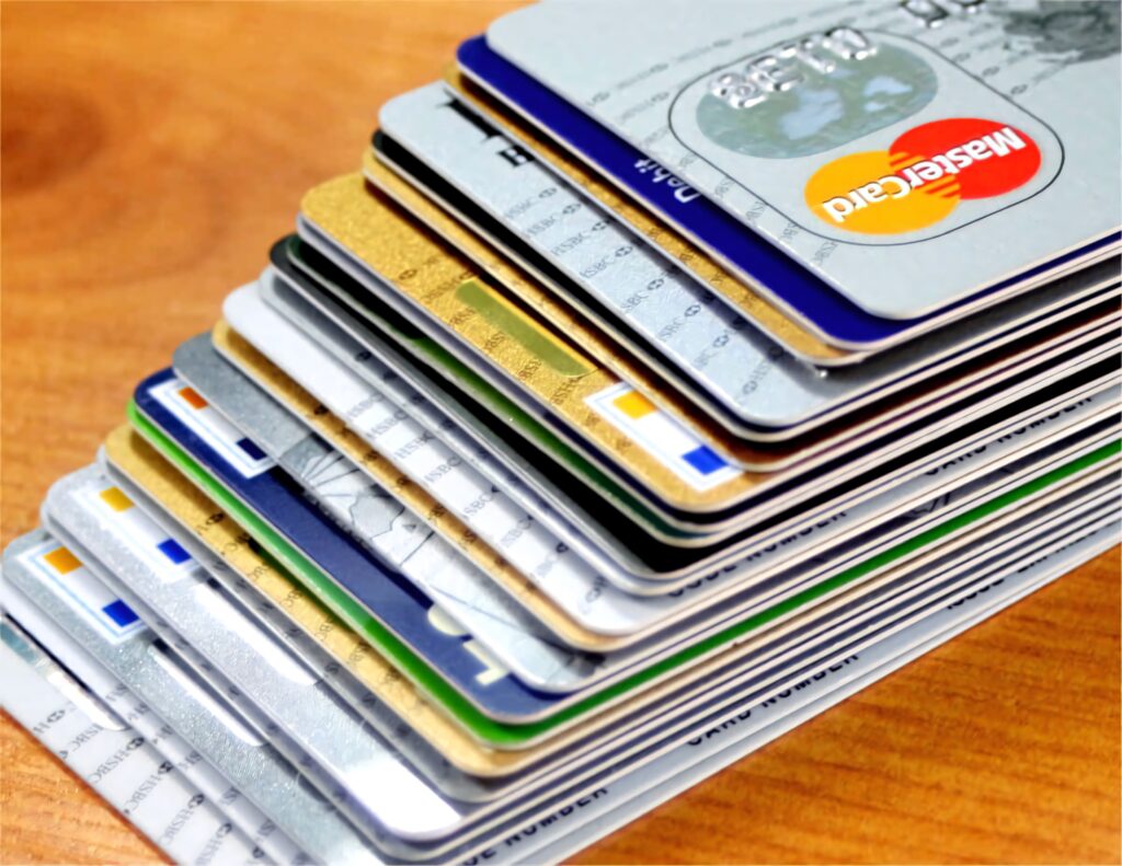 Stack of diverse credit cards on wood table displaying metallic pastel colors and banking logos Wallpaper