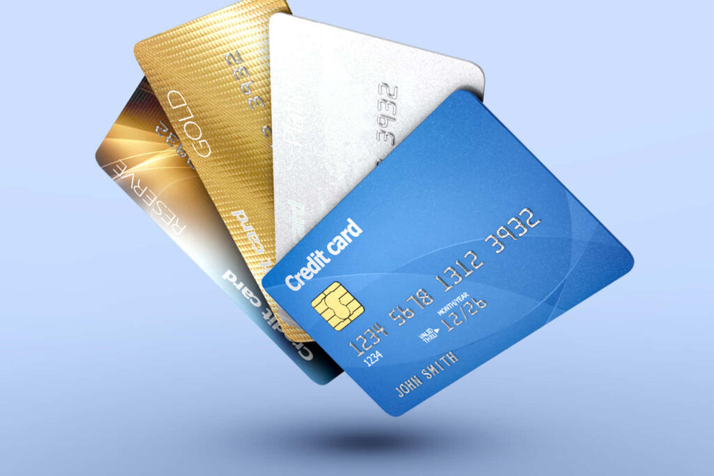 Four modern credit cards in blue silver gold and white hover over a soft gradient sky background Wallpaper