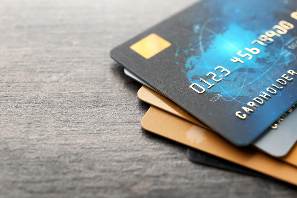 Close-up of stacked black gold and blue credit cards on wooden table highlighting finance security Wallpaper