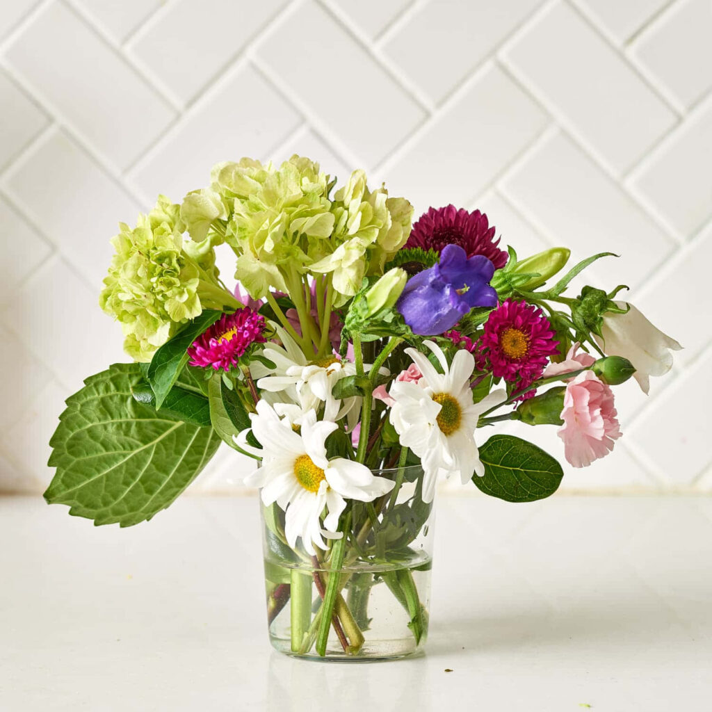 Modern Flower Arrangement in Clear Vase with Classic Tiled Background Wallpaper