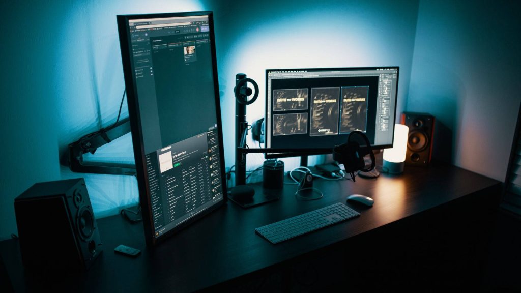 Modern gaming desktop with dual monitors blue backlight studio speakers sleek keyboard setup Wallpaper