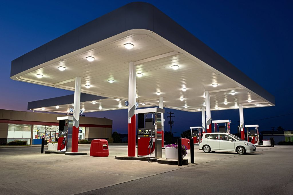 Modern gas station at twilight with sleek fuel pumps and parked hatchback 3D wallpaper background