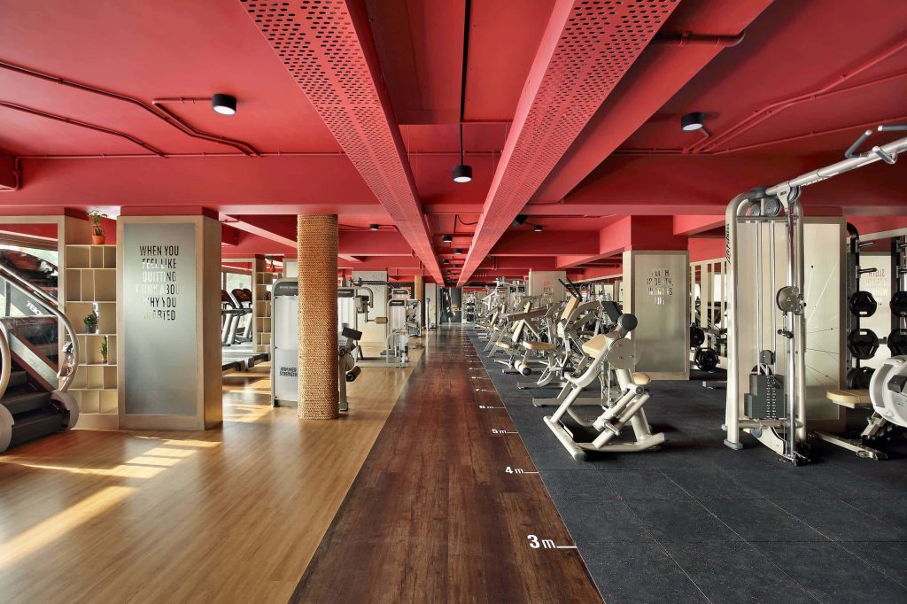 Modern gym interior with bold red ceiling strength machines and warm wood flooring background Wallpaper