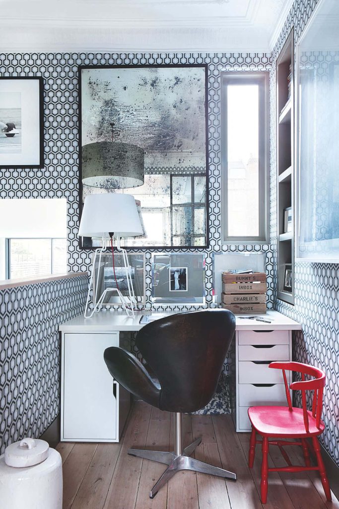 Modern home office with dark leather swivel chair red accent chair white desk geometric wallpaper