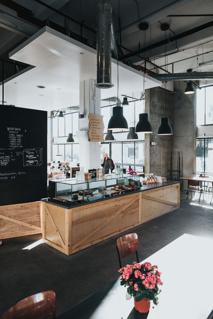 Modern cafe interior wallpaper with concrete walls wooden counter exposed ductwork and chalkboard menu