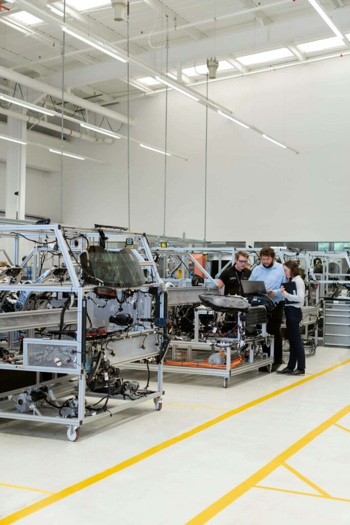 Modern industrial factory with workers collaborating near machinery in a bright organized workspace Wallpaper