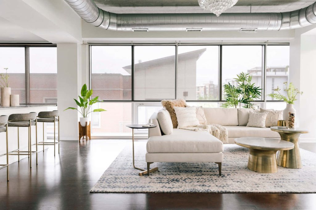 Modern industrial loft Zoom background with cream sectional and brass coffee tables interior Wallpaper
