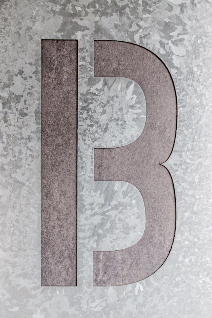 Etched letter B on textured metallic background modern industrial style wallpaper design