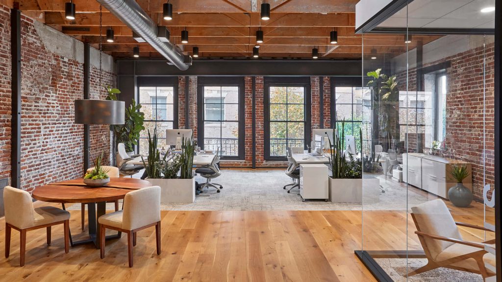 Modern industrial Zoom office background with exposed brick, hardwood floors, and greenery Wallpaper