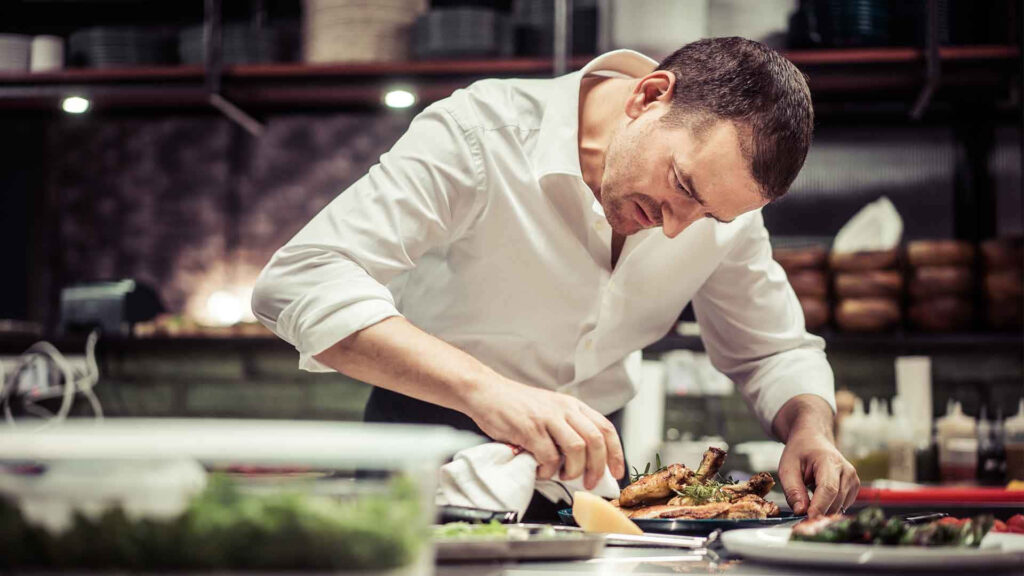 Chef Perfecting Gourmet Dishes in a Modern Kitchen Wallpaper