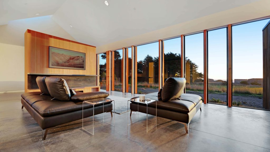 Modern living room Zoom background with dark leather sofas glass tables and sunset view Wallpaper