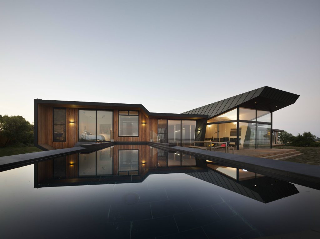 Modern luxurious house wallpaper with sleek wood design glass walls and reflective pool at dusk