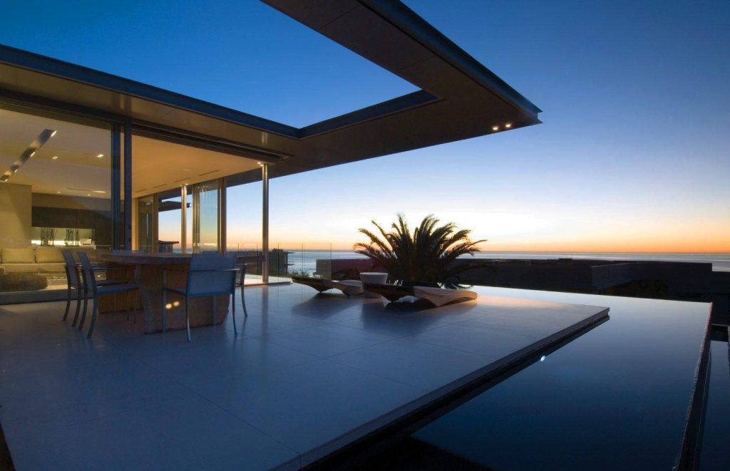 Modern house with infinity pool at sunset blending minimalist design and ocean horizon background Wallpaper
