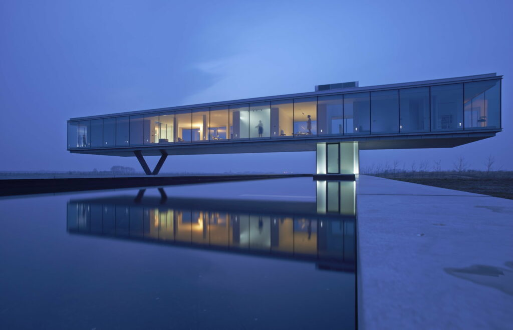Modern glass villa cantilevered over reflecting pool at twilight with warm interior lighting reflection Wallpaper