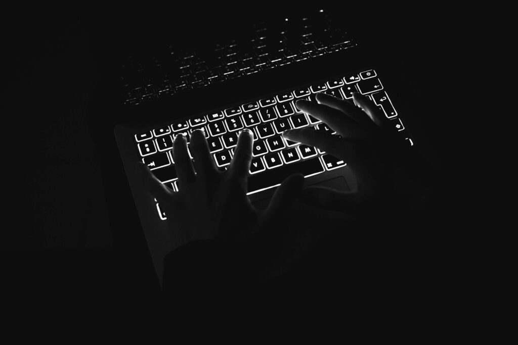 Minimalist Wallpaper: Hands Typing on a Backlit Keyboard in Dark