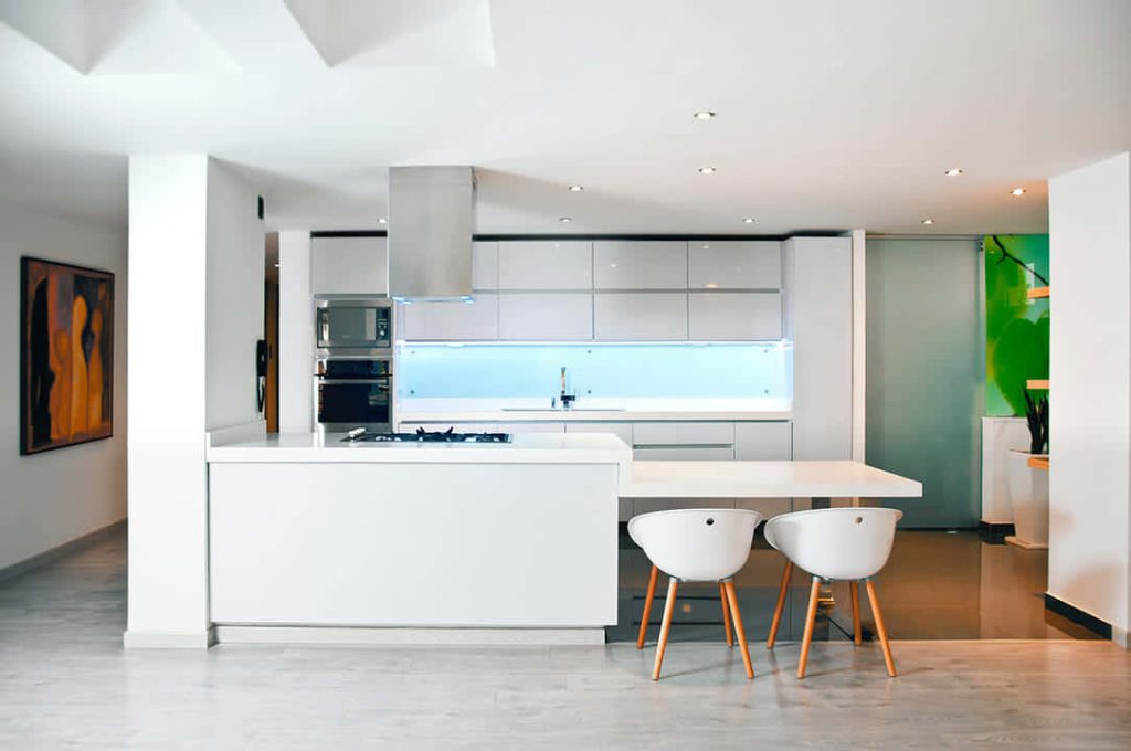 Modern white kitchen wallpaper with island sleek cabinets and white bar stools for Zoom background