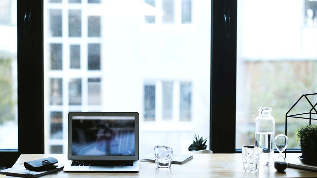 Minimalist bright office Zoom meeting wallpaper laptop water bottle hourglass wooden desk background