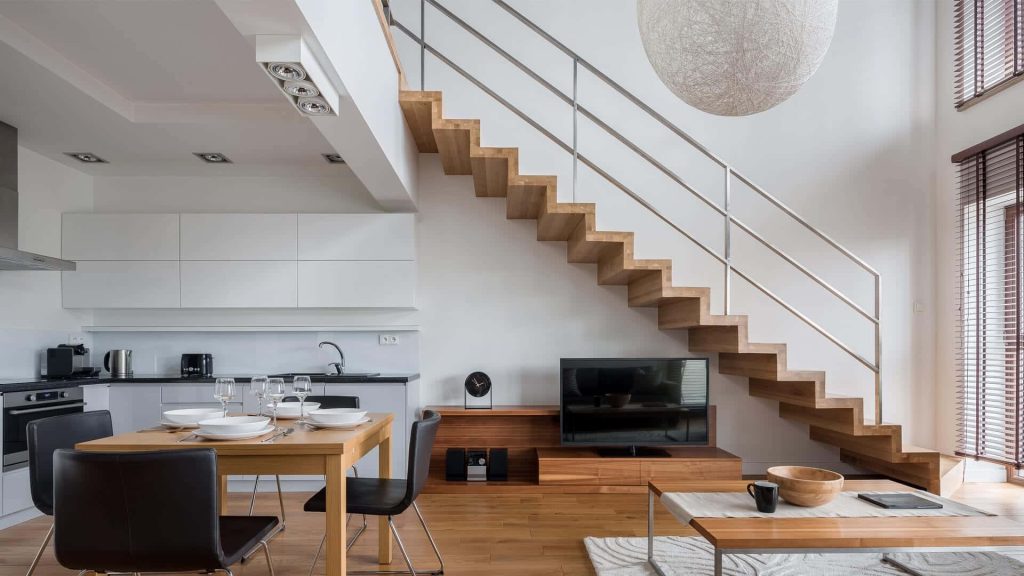Modern open-plan interior with bright kitchen dining area and wooden open-riser staircase background Wallpaper