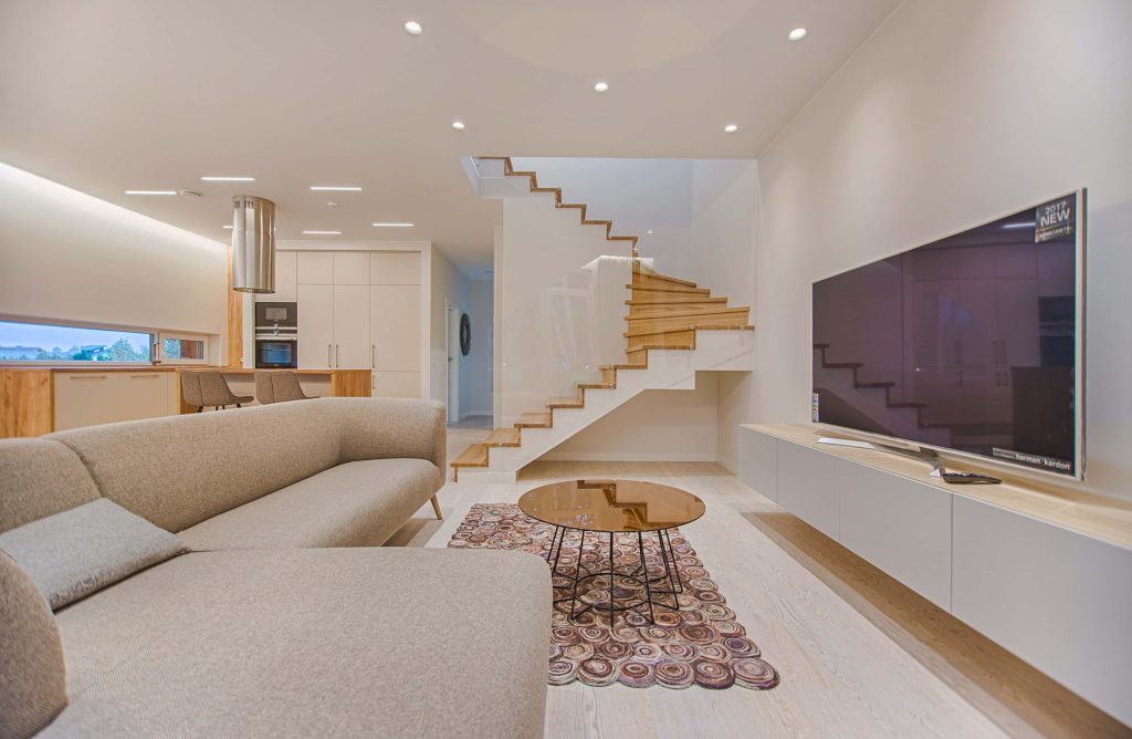 Modern open-plan living room with sectional sofa floating staircase glass coffee table TV Wallpaper