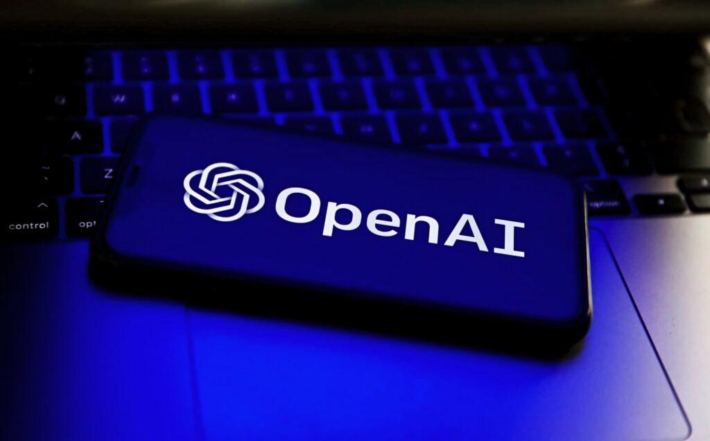 Smartphone screen with OpenAI logo glowing blue on laptop keyboard minimalist tech wallpaper