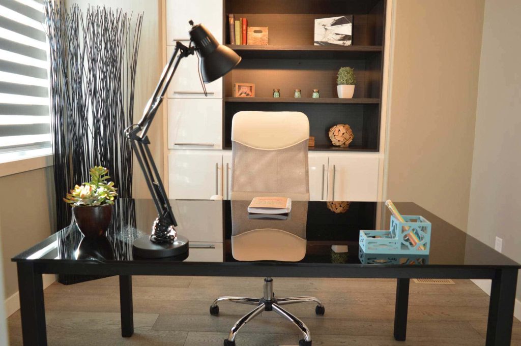 Modern home office workspace with black desk white chair and organized bookshelf background Wallpaper