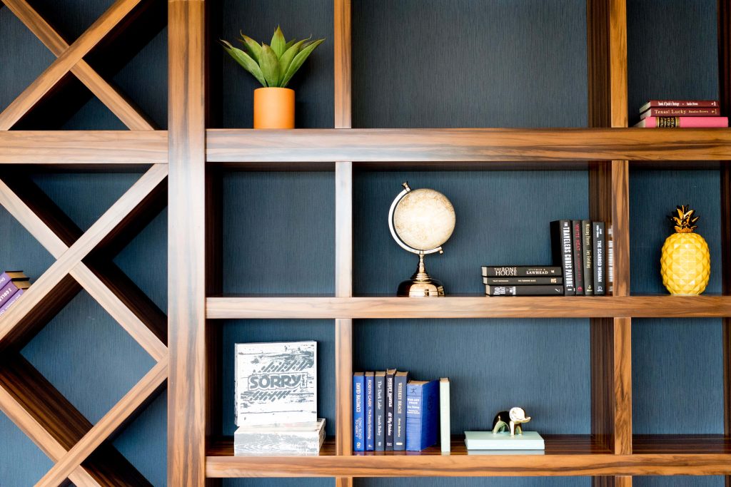 Professional Zoom background with geometric wooden shelves navy wall books globe gold pineapple Wallpaper