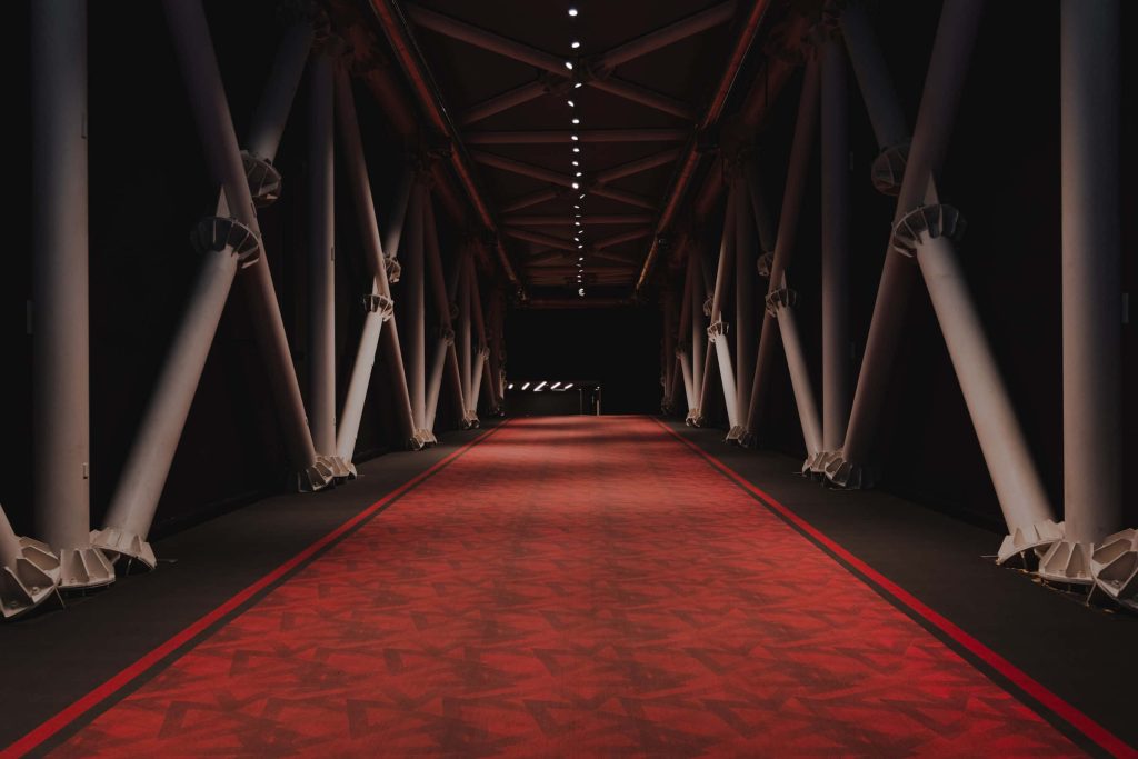 Modern red carpet wallpaper with bold geometric patterns and white industrial truss frame
