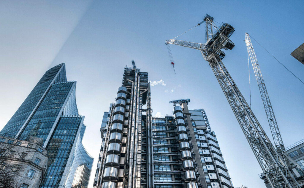Modern skyscrapers with glass facades and a construction crane in a vibrant cityscape background Wallpaper