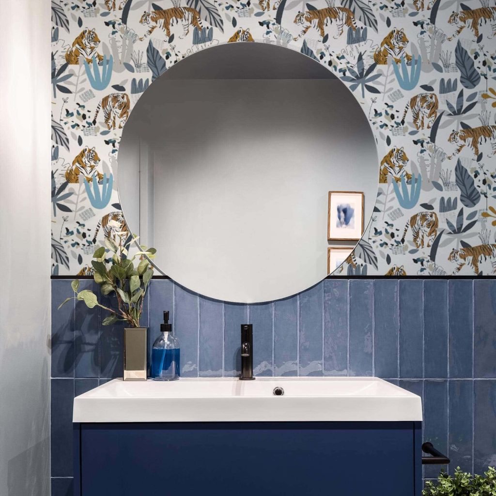 Modern bathroom with tiger print wallpaper blue vertical tiles dark vanity and round mirror