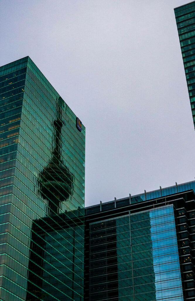 Reflection of tower on glass skyscraper with deep greens and cool blue tones wallpaper background