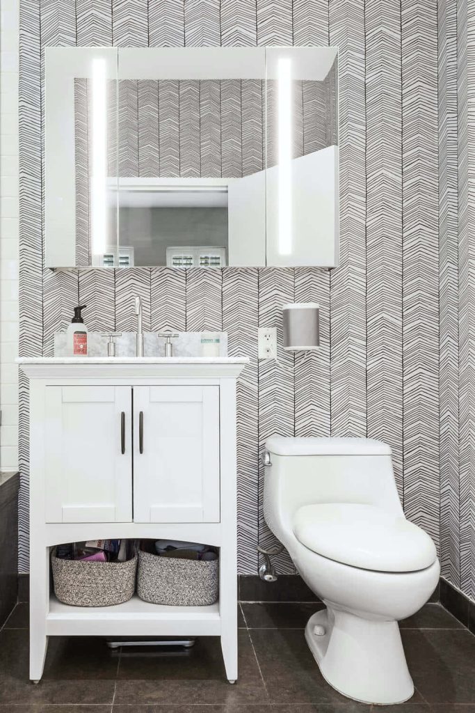 Modern white bathroom with black and white arrow wallpaper LED mirror white vanity dark tile floor