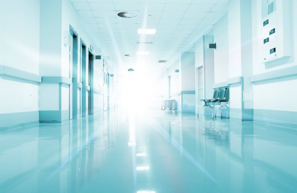 Bright modern all-white hospital corridor with reflective floor and waiting chairs in perspective Wallpaper