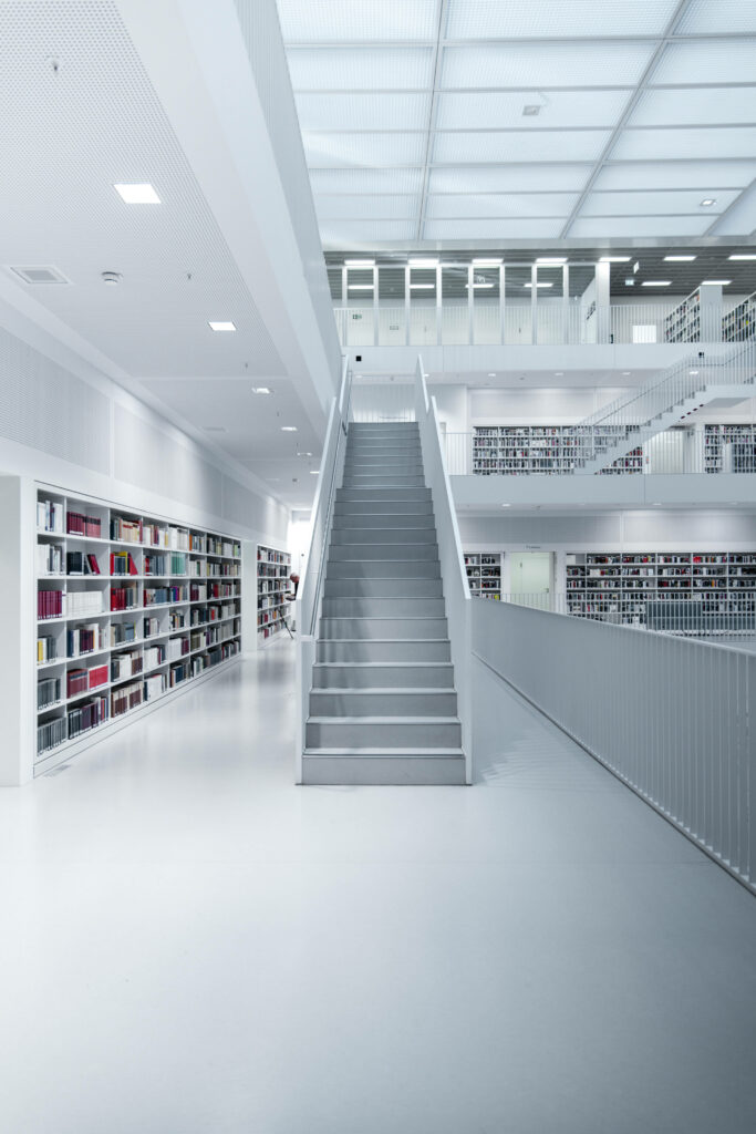 Modern white minimalist library interior with open staircase and colorful bookshelves wallpaper