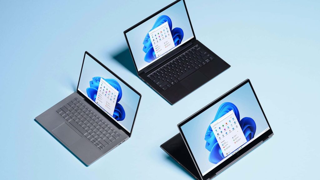 Three sleek laptops on blue background showing Windows 11 with Microsoft Office apps open Wallpaper