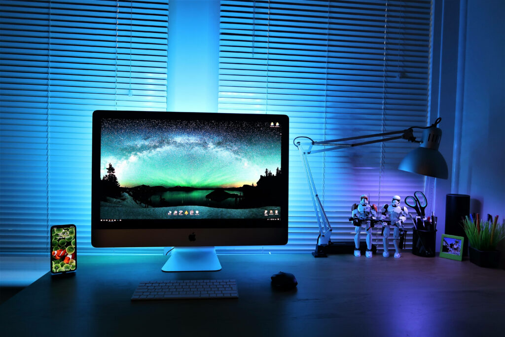 Modern workspace with iMac galaxy wallpaper and detailed Clone Trooper figures under blue light