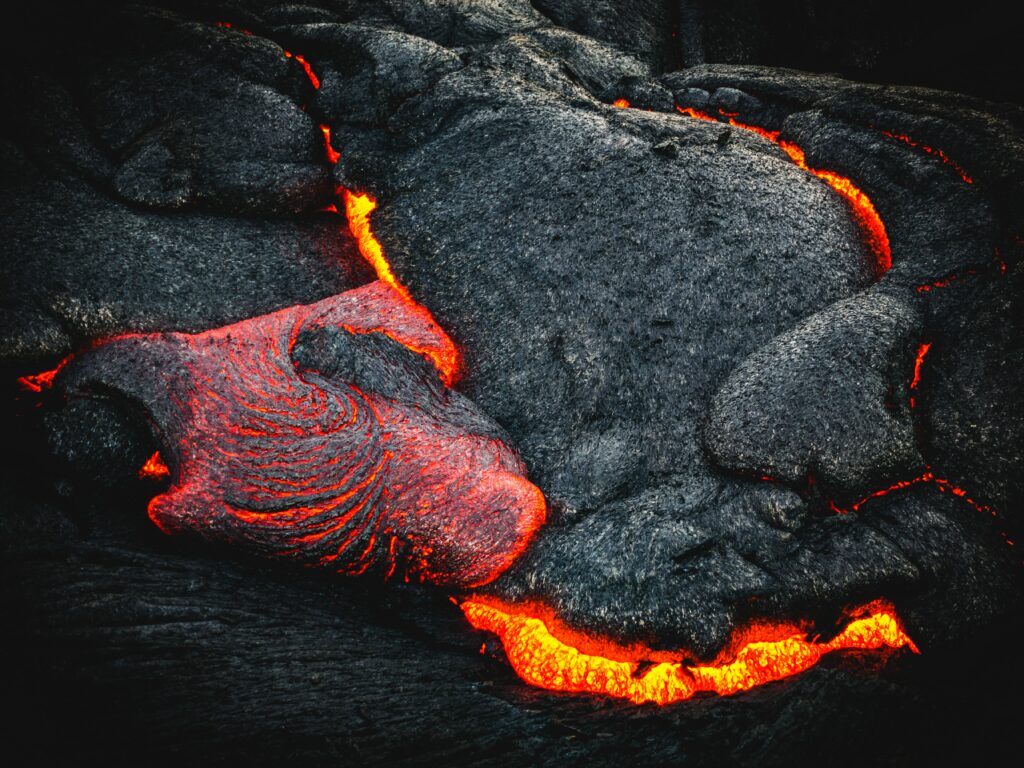 Molten lava flowing over volcanic rocks glowing fiery red and orange against dark crust background Wallpaper